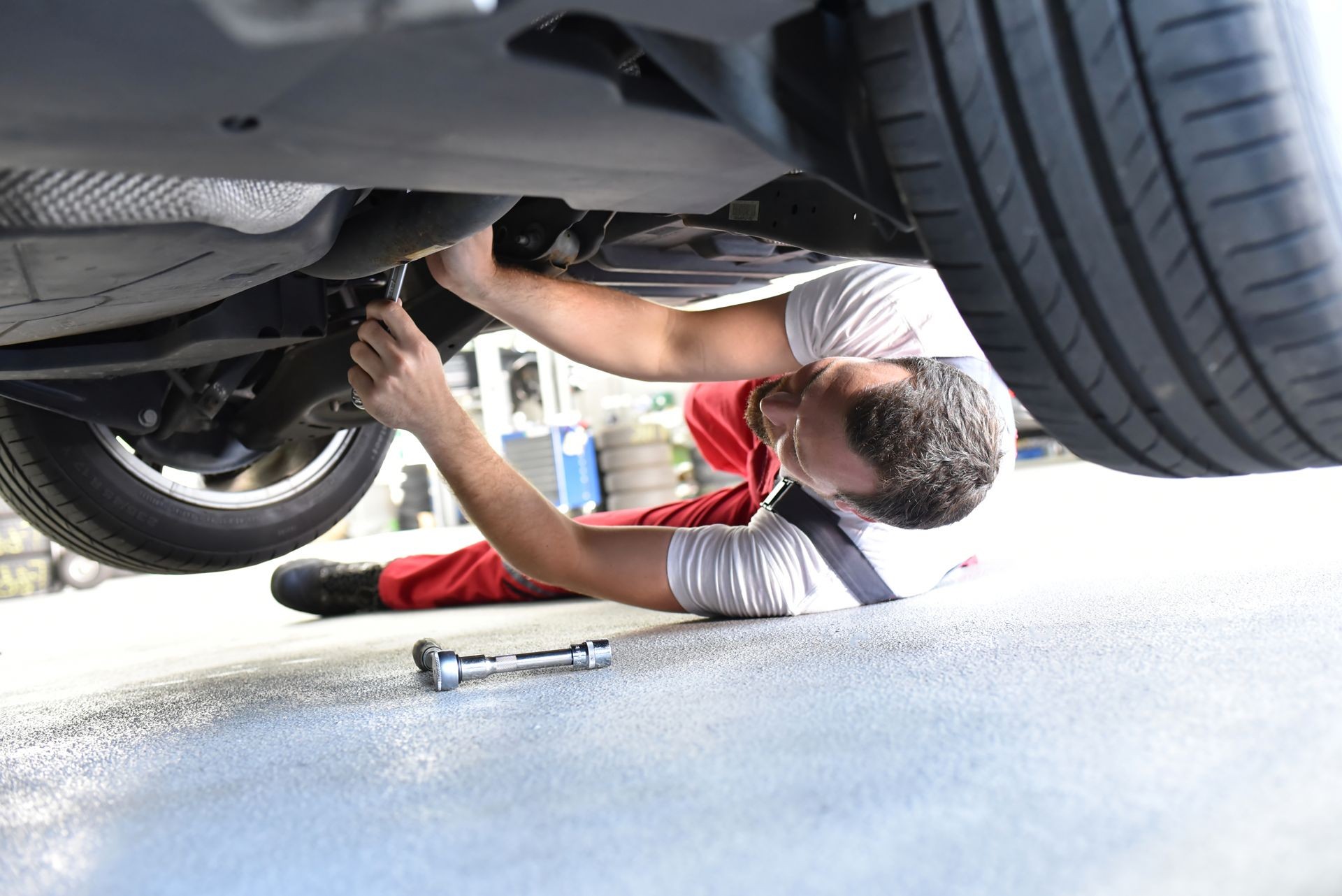 car mechanic in work clothes works in a workshop and repairs a vehicle 